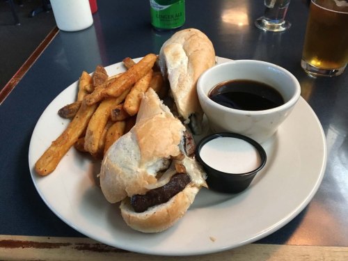 A plate with two sandwiches, fries, and dipping sauces on a blue table.