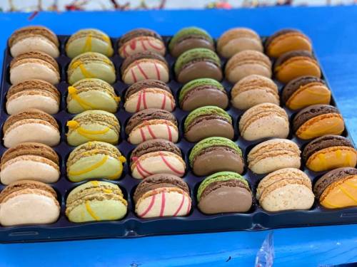 A colorful assortment of macarons arranged neatly in a tray, featuring various flavors and decorative drizzles.