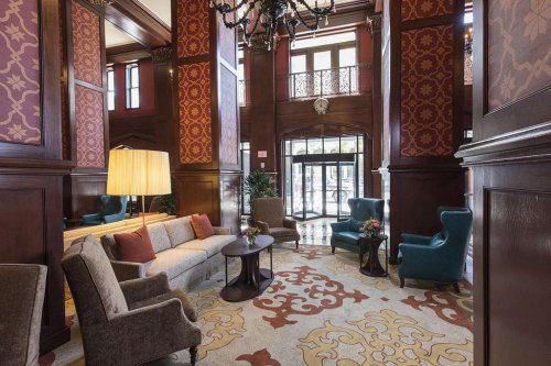 Elegant hotel lobby featuring plush seating, ornate decor, and large windows with natural light.