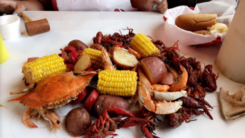 A colorful seafood feast featuring crabs, shrimp, crawfish, corn, and potatoes on a table.