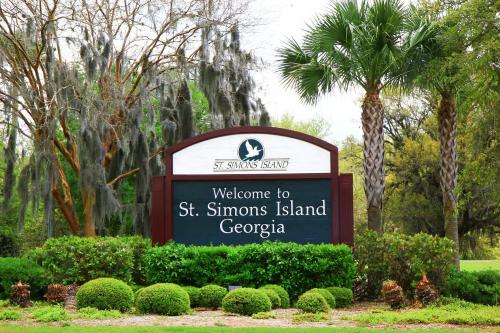 Welcome sign for St. Simons Island, Georgia, surrounded by greenery and palm trees.