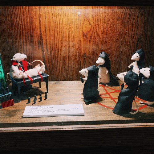 A display of toy mice in robes, one seated on a chair, surrounded by others in a whimsical courtroom scene.