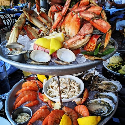 A seafood platter featuring crabs, shrimp, oysters, clams, and lemon slices on a two-tiered serving dish.