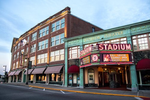 Exterior of the Stadium Theatre, featuring a marquee and colorful architecture, with a clear sky in the background.