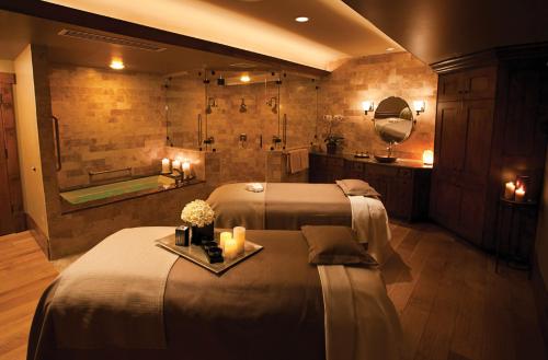 A serene spa room with two massage tables, candles, and soft lighting, creating a relaxing atmosphere.