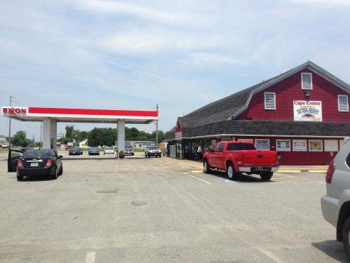 A red building with a sign for "Cape Center" next to an Exxon gas station, with parked cars in the lot.