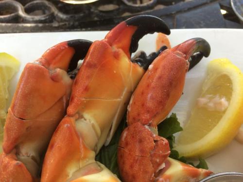 Close-up of crab claws on a plate, garnished with lemon wedges and leafy greens.