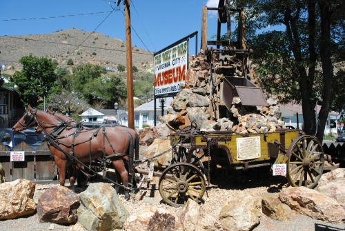 A historic horse-drawn mining cart with rocks, displayed outside a museum in Virginia City, surrounded by boulders.
