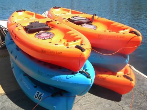 Colorful kayaks stacked by the water at Wood Canyon Lake, with orange and blue boats ready for use.