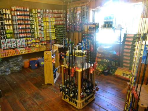A well-stocked fishing tackle shop with various rods, reels, and bait displayed on shelves and racks.
