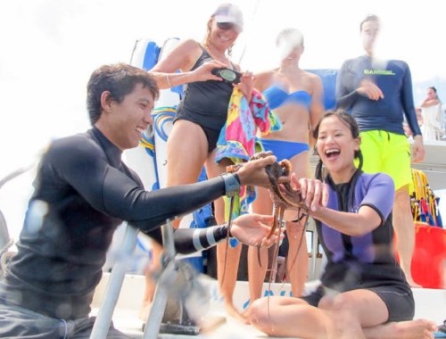 A group of people on a boat, smiling and interacting with an octopus during a fun underwater adventure.