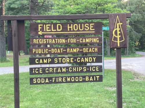 Wooden sign for a field house listing amenities: camping registration, boat ramp, camp store, and snacks.