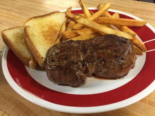 A plate with a grilled steak, golden fries, and two slices of toasted bread.