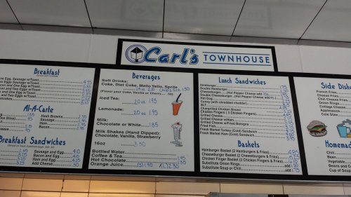 Menu board at Carl's Townhouse featuring breakfast, lunch sandwiches, beverages, and sides with prices listed.
