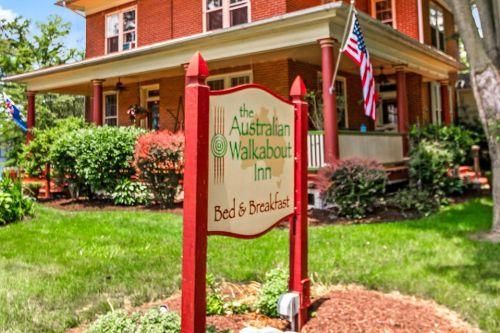 Sign for "The Australian Walkabout Inn Bed & Breakfast" in front of a charming red-brick house with greenery.