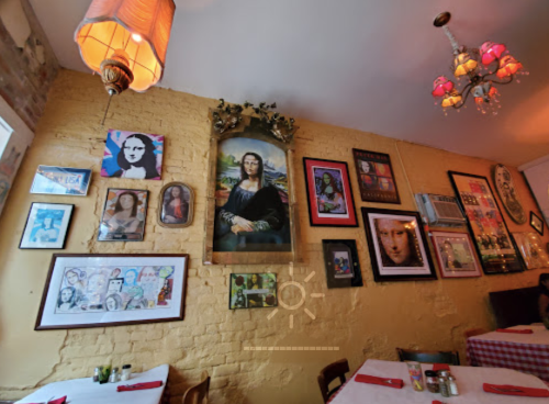 A cozy restaurant wall adorned with various framed art pieces, including a large portrait of the Mona Lisa.