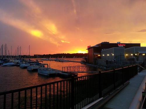 Sunset over a marina with boats, featuring vibrant orange and purple skies and a restaurant by the water.