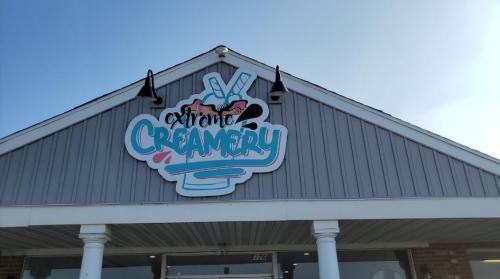 Sign for "Extreme Creamery" on a building with a blue sky in the background.