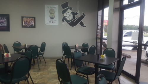 Interior of a casual dining space with tables, chairs, and a wall mural of a character in a top hat.