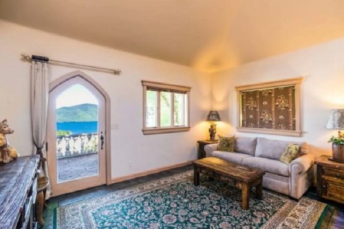 Cozy living room with a view of a lake through an arched door, featuring a sofa and wooden coffee table.