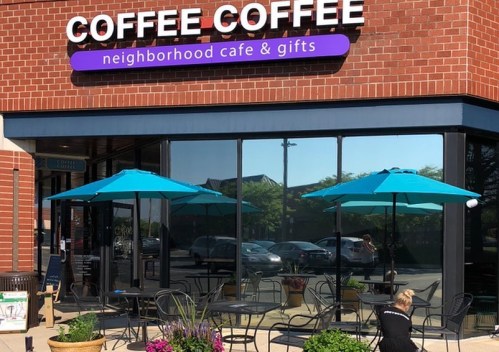 A neighborhood café with outdoor seating, featuring turquoise umbrellas and a sign that reads "Coffee Coffee."