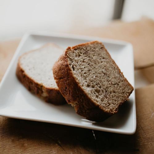 Two slices of freshly baked bread on a white plate, resting on a wooden surface.