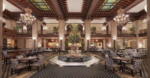Elegant hotel lobby featuring a grand fountain, ornate chandeliers, and stylish seating areas with rich decor.
