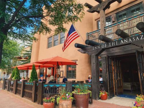 Exterior of the Inn of the Anasazi, featuring outdoor seating, umbrellas, and an American flag.