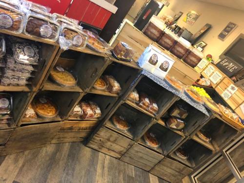 A display of various baked goods in wooden crates, including pies, cakes, and pastries, in a cozy shop setting.