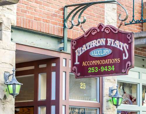 Sign for "Hiatron Flats" luxury accommodations, featuring a decorative design and contact number.