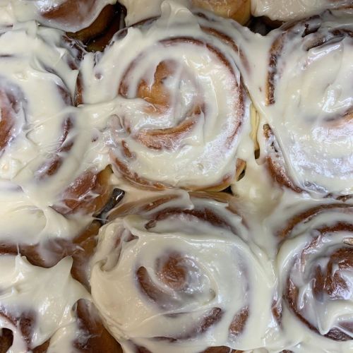 Close-up of freshly baked cinnamon rolls topped with creamy white icing.