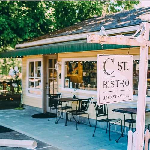 A charming bistro with a sign reading "C St. Bistro" in Jacksonville, featuring outdoor seating and a welcoming atmosphere.