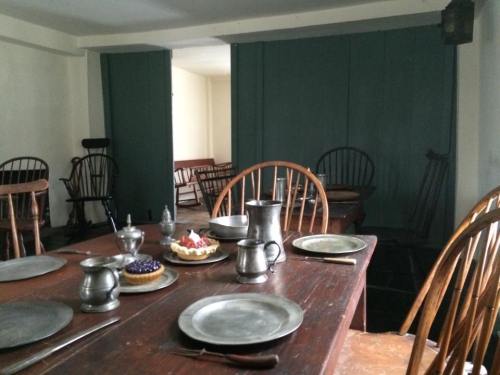 A rustic dining room with wooden tables, chairs, and plates set for a meal, featuring cakes on the table.
