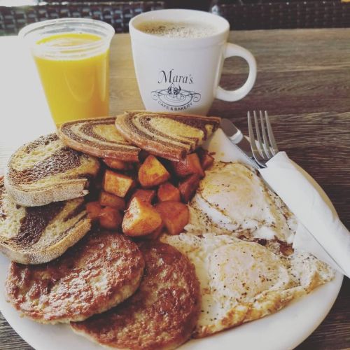 A hearty breakfast plate with eggs, sausage, potatoes, toast, and a cup of coffee and orange juice on the side.
