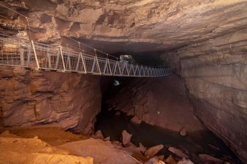 A suspended bridge crosses a dark cave with rocky terrain and a small waterway below.