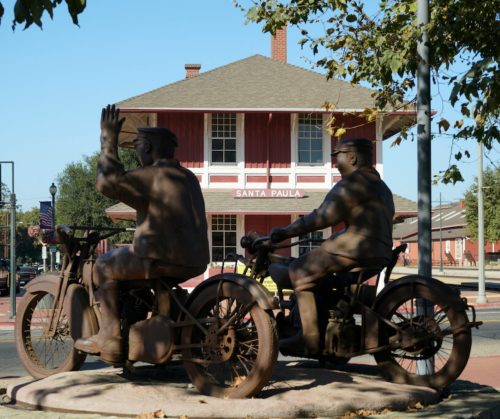 Statues of two men on motorcycles in front of the historic Santa Paula train station.