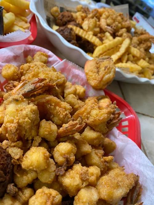 A close-up of a basket filled with fried shrimp and a side of crinkle-cut fries.