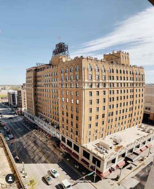 Historic brick hotel with ornate architecture, overlooking a city street under a clear blue sky.