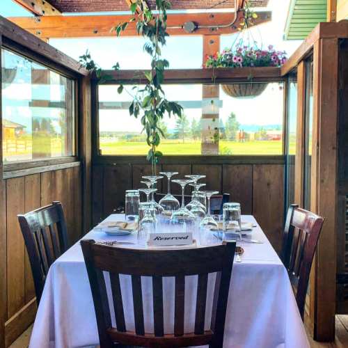 A reserved table set for dining, surrounded by wooden walls and large windows with a view of greenery outside.