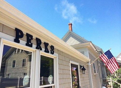 A building with the sign "PERKS" and an American flag, under a clear blue sky.