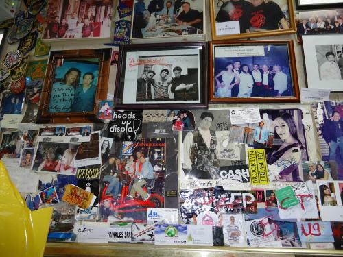 A collage of framed photos, memorabilia, and posters covering a wall, showcasing various people and events.