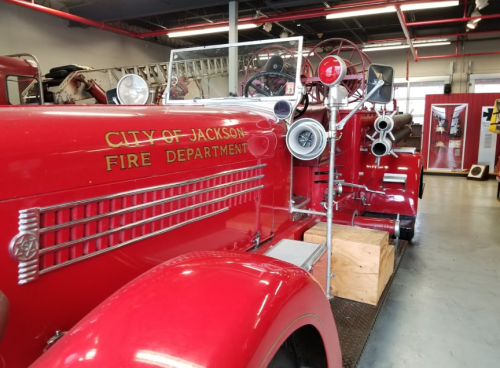 A vintage red fire truck from the City of Jackson Fire Department displayed indoors.