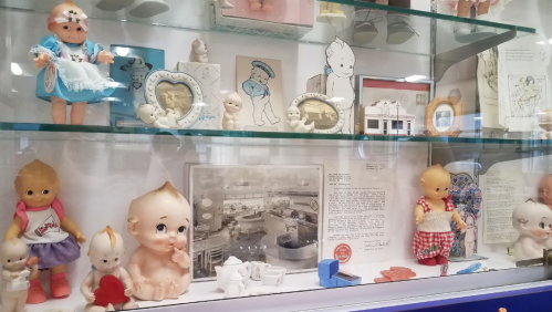 A display case filled with vintage dolls, figurines, and memorabilia, showcasing various styles and designs.