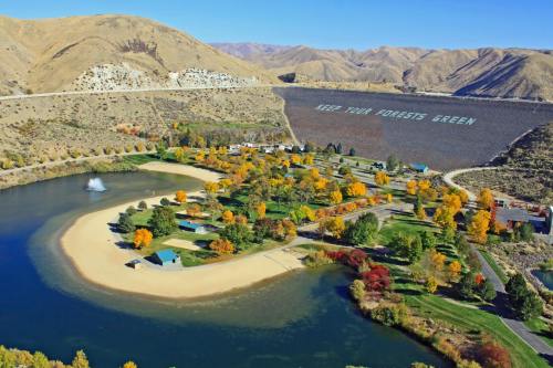 A scenic view of a park with a pond, surrounded by autumn trees and mountains, featuring a message on the hillside.