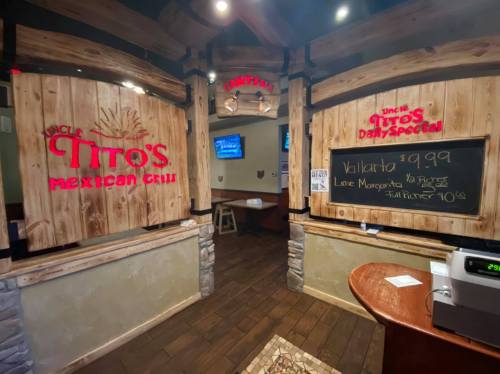 Interior of a restaurant featuring wooden signs for "Uncle Tito's Mexican Grill" and daily specials on a chalkboard.