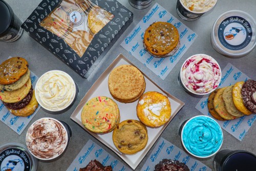 A variety of colorful cookies and ice cream cups arranged on a table, featuring a box of baked goods in the center.