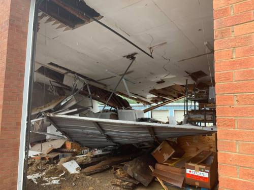 A collapsed ceiling and damaged interior of a building, with debris scattered on the floor.
