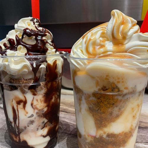 Two dessert cups: one with chocolate sauce and whipped cream, the other with caramel sauce and a creamy layer.
