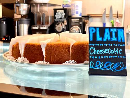 A plate of plain cheesecake slices displayed with a decorative sign in a café setting.