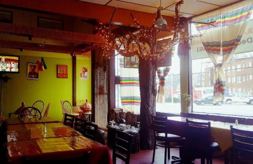 Cozy restaurant interior with colorful decor, wooden tables, and a large window showcasing a street view.